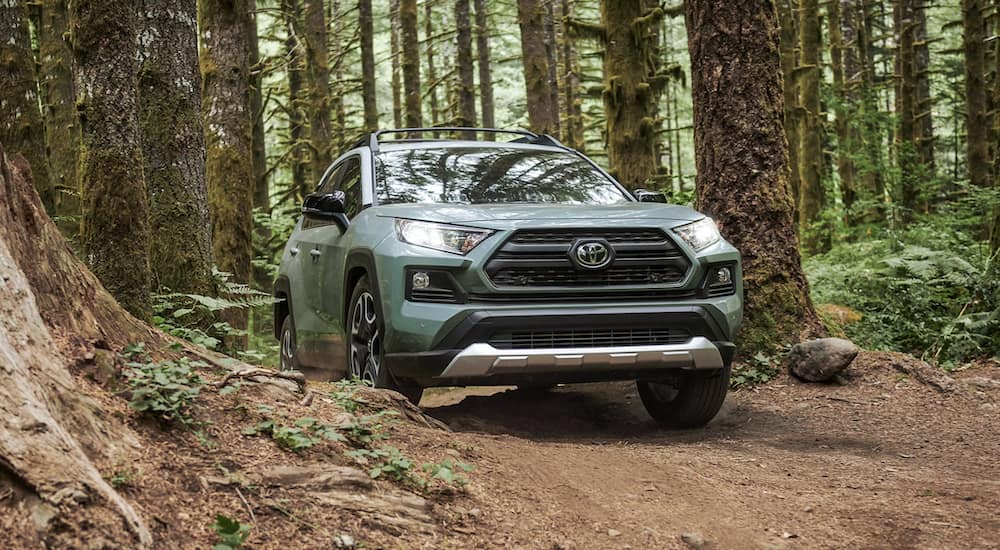 A green 2021 Toyota RAV4 is off-roading in a forest.