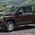 A brown 2021 Chevy Silverado 2500 is parked on a dirt road in front of mountains.