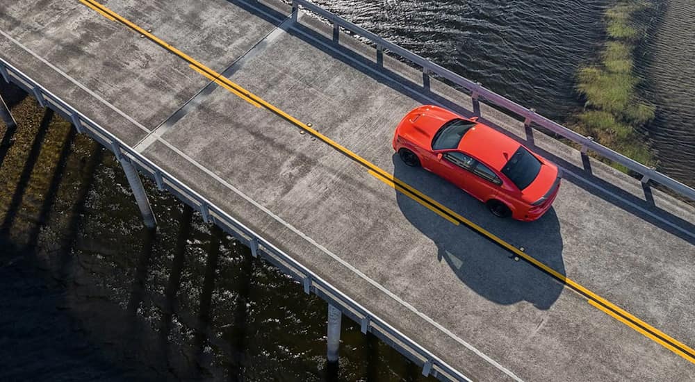 A red 2021 Dodge Charger is shown from above driving over a bridge.