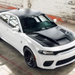 A black and white 2021 Dodge Charger is parked in a modern garage.