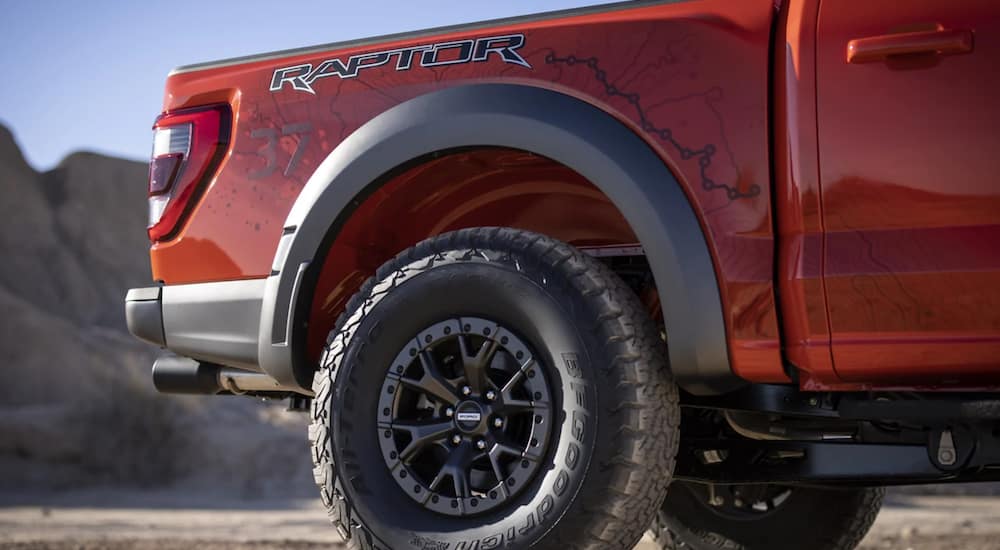 A red 2021 Ford F-150 Raptor shows a close up of the rear tire.