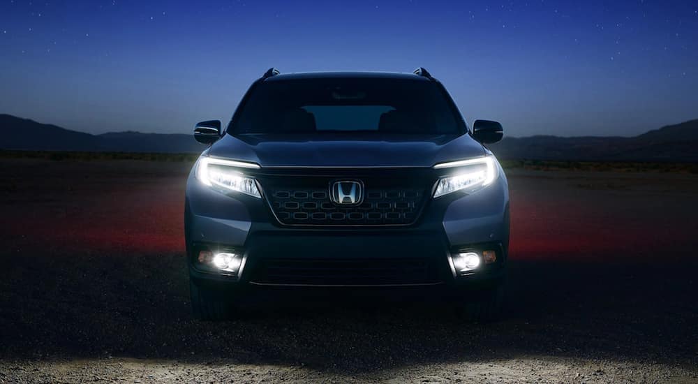 The front of a 2021 Honda Passport Elite is shown at dusk.
