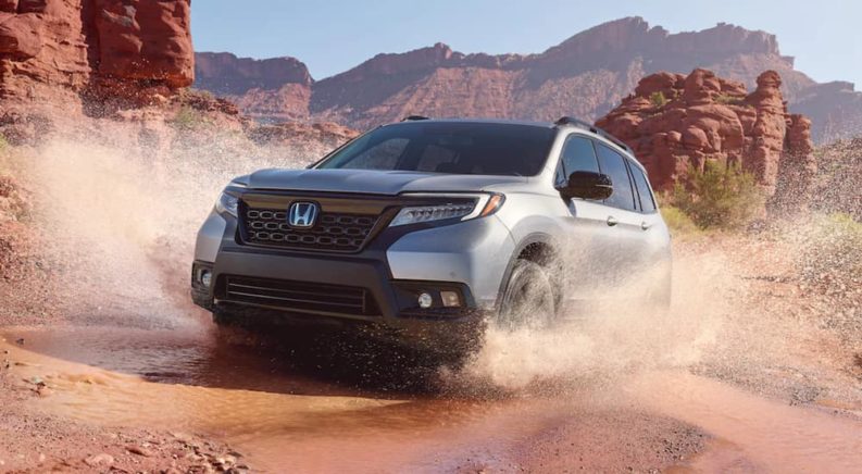 A white 2021 Honda Passport AWD Elite is driving through a desert.