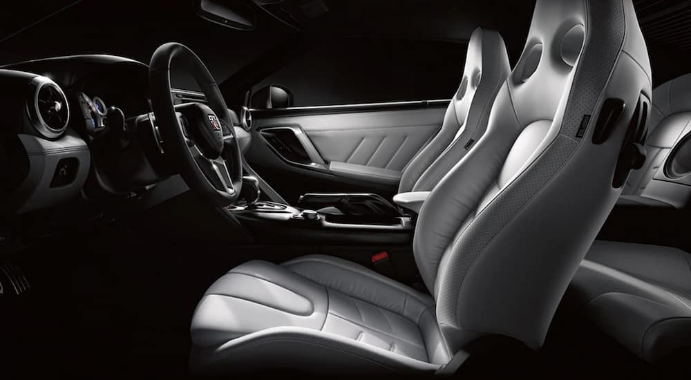 The grey interior of a 2021 Nissan GT-R shows the front seats and steering wheel.