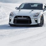 A white 2021 Nissan GT-R is driving on a snow covered road.