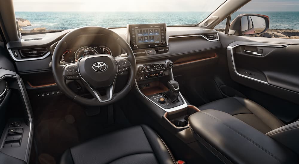 The interior of a 2021 Toyota RAV4 shows the steering wheel and infotainment screen.