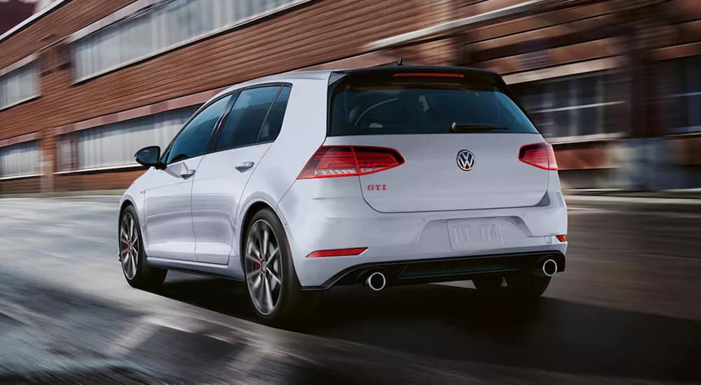 A white 2021 Volkswagen Golf GTI is shown from the back driving through a city.