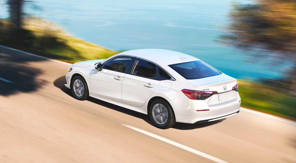 A white 2022 Honda Civic LX is shown from a high angle driving past a lake.