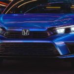 A blue 2022 Honda Civic Sport is shown from the front at night.