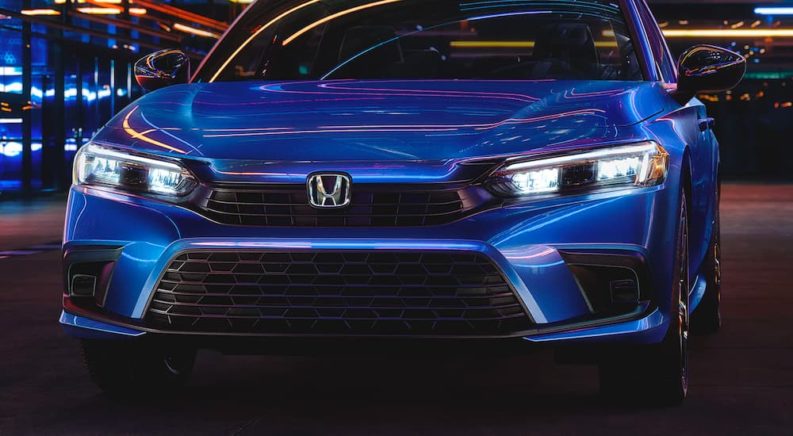 A blue 2022 Honda Civic Sport is shown from the front at night.