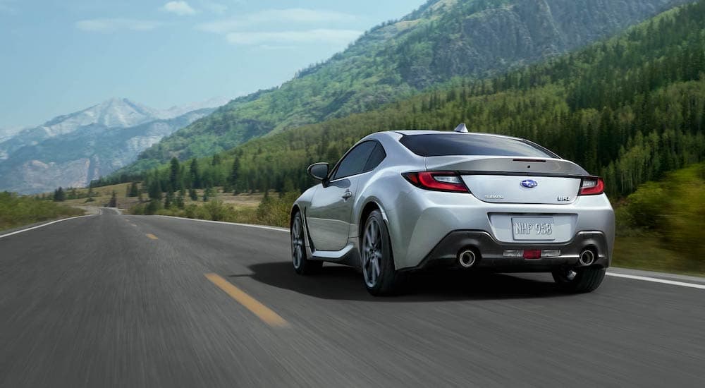 A silver 2022 Subaru BRZ is shown from the rear driving toward distant mountains.