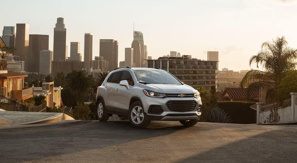 A silver 2021 Chevy Trax is parked on the top of a hill overlooking the city.