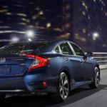A blue 2021 Honda Civic Sedan EX is shown from the back driving through a city after leaving a Honda Civic Dealer.