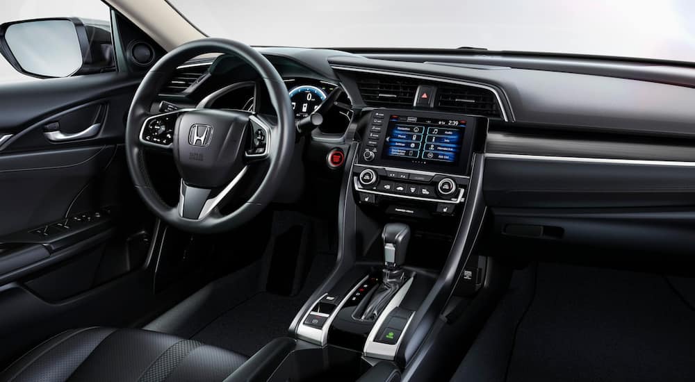 The interior of a 2021 Honda Civic Sedan Touring shows the steering wheel and infotainment screen.