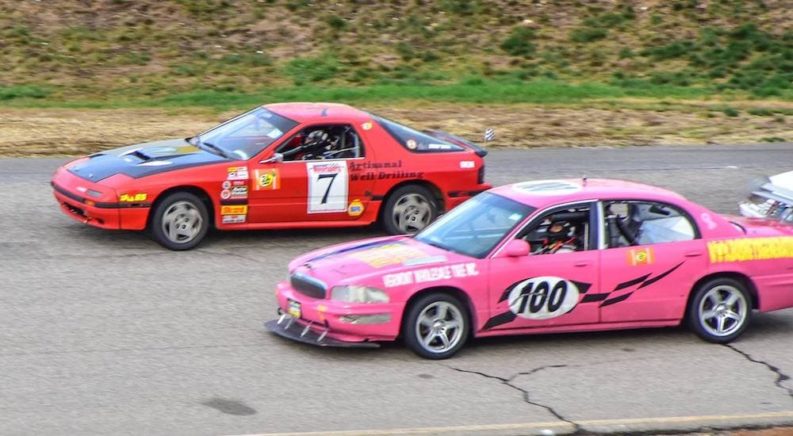A red Mazda RX-7 FC is shown driving next to a pink Buick Park Avenue.