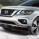 A silver 2020 Nissan Pathfinder is shown from the front driving through snow.