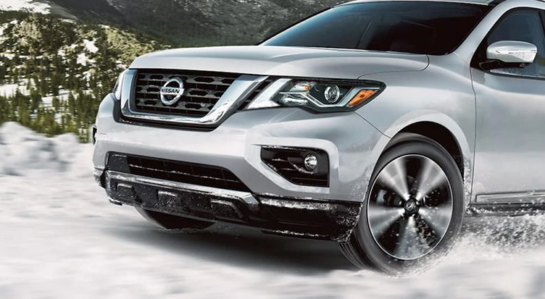 A silver 2020 Nissan Pathfinder is shown from the front driving through snow.