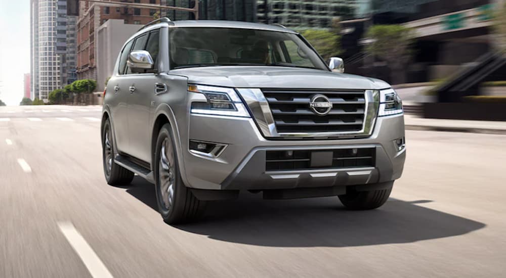 A silver 2021 Nissan Armada is shown from the front driving through a city.
