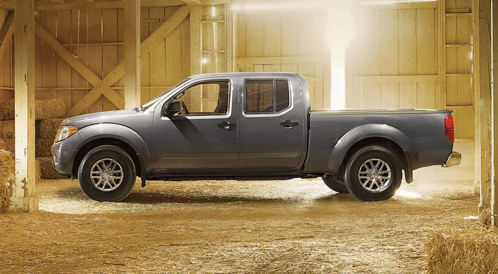 A grey 2021 Nissan Frontier is parked in a barn filled with hay after leaving a Nissan dealer.