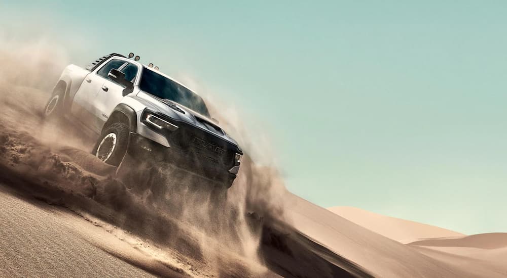 A white 2021 Ram 1500 TRX is driving through a desert sand.