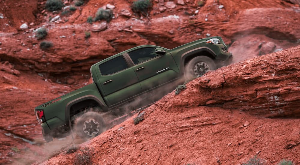 A green 2021 Toyota Tacoma is driving up a hill in the desert.