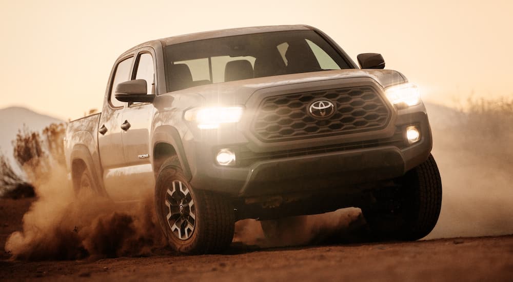A grey 2021 Toyota Tacoma is shown from the front driving at dusk in a desert.