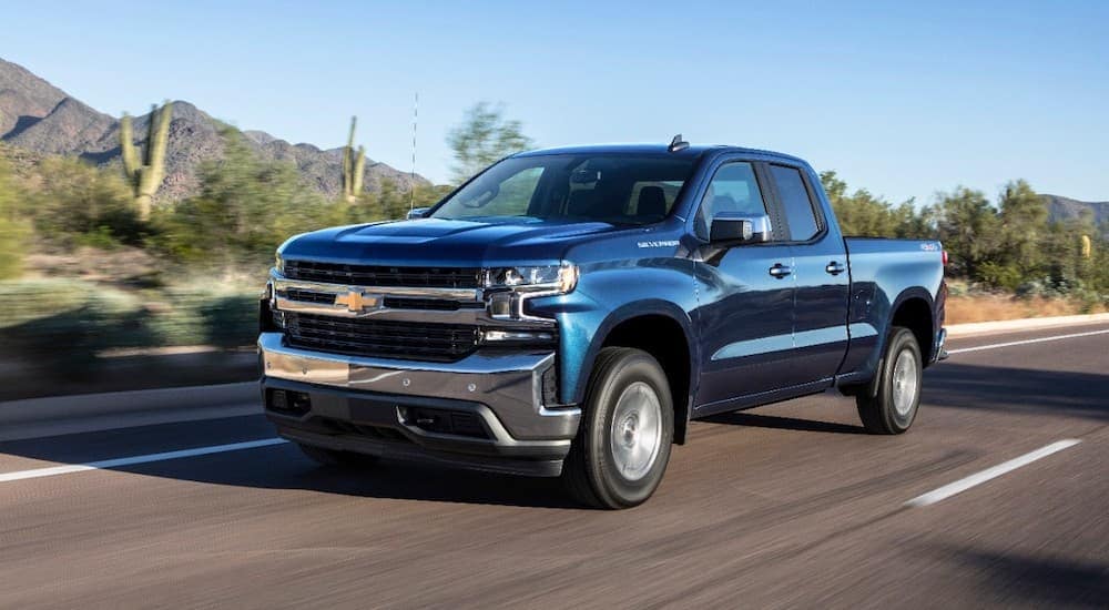 A blue 2019 Chevy Silverado is driving on a highway through a desert.