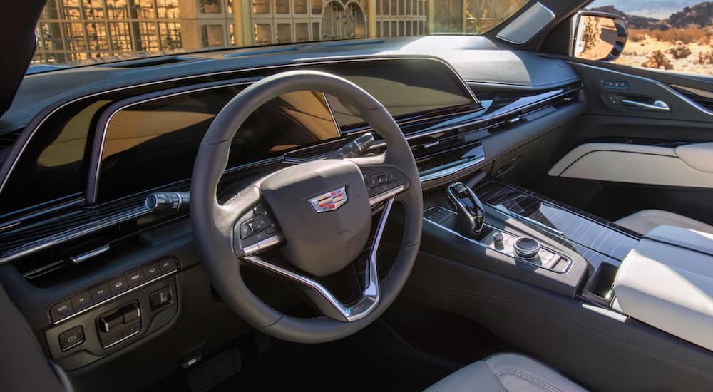 The interior of a 2021 Cadillac Escalade shows the steering wheel and infotainment screen.