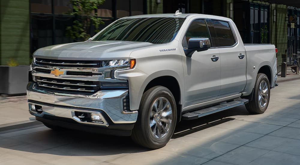 A grey 2021 Chevy Silverado 1500 is parked in front of a city building.