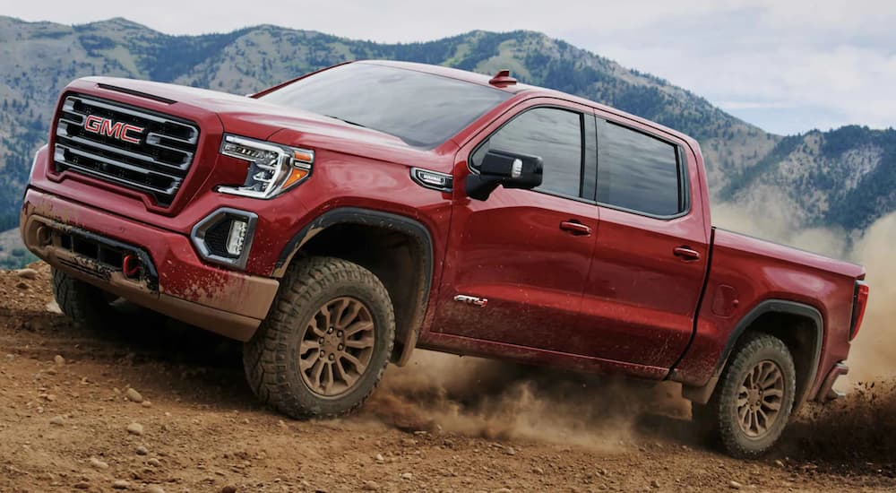 A red 2021 GMC Sierra 1500 is off-roading in the mountains.