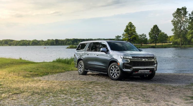 A grey 2021 Chevy Suburban is shown parked on a lake shore.