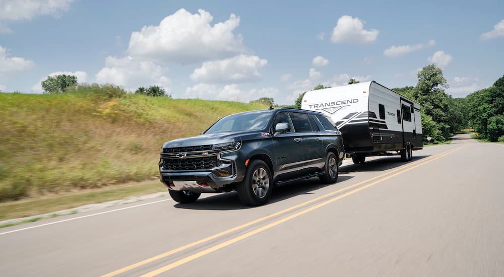 A black 2021 Chevy Suburban Z71 is shown towing a trailer down an empty road.