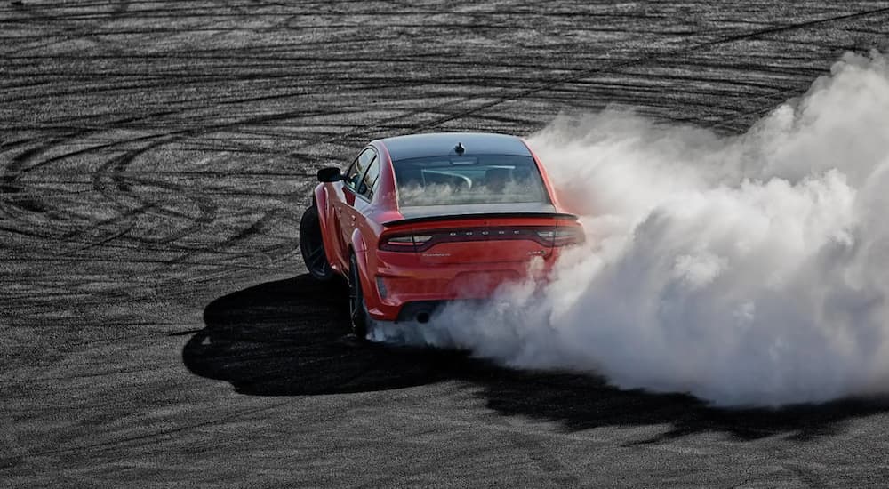 An orange 2021 Chevy Camaro is doing a burnout on a racetrack.