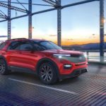 A red 2021 Ford Explorer is driving over a bridge after winning a 2021 Ford Explorer vs 2021 Chevy Traverse comparison.