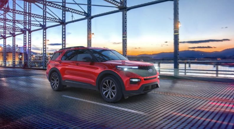 A red 2021 Ford Explorer is driving over a bridge after winning a 2021 Ford Explorer vs 2021 Chevy Traverse comparison.