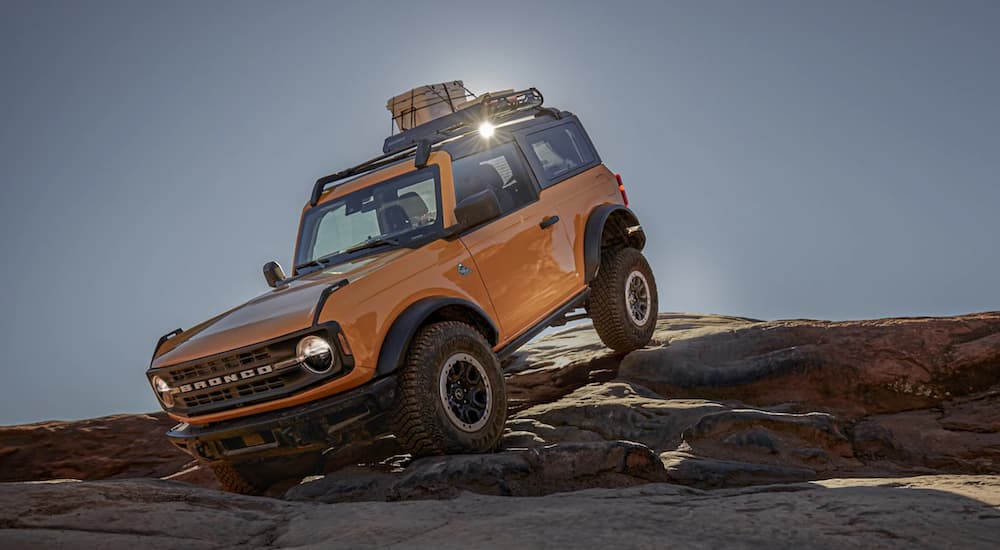 An orange 2021 Ford Bronco is shown off-roading on rocks.