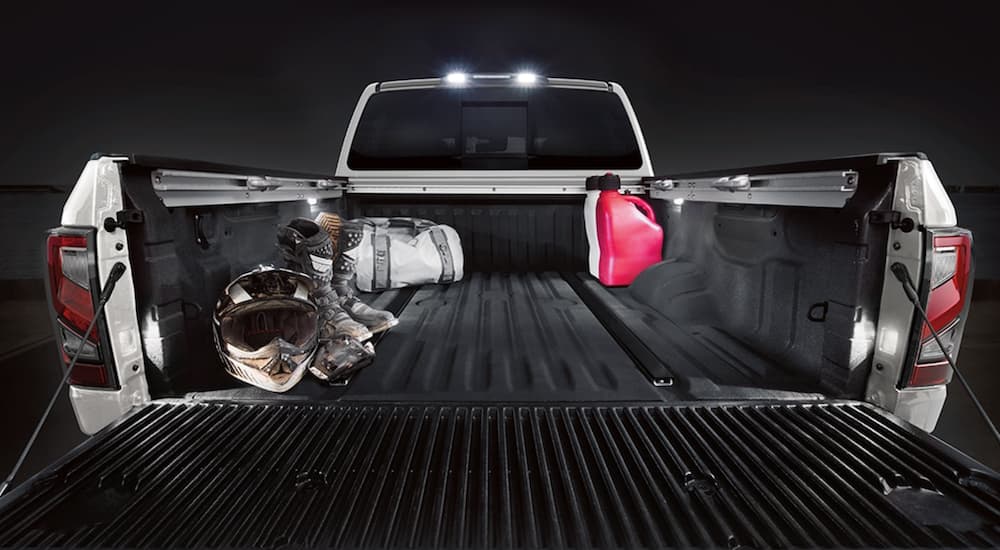 The truck bed of a 2021 Nissan Titan is shown filled with dirt bike gear and gas canisters.