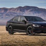 A black 2021 Volkswagen Jetta GLI is parked on dirt with distant mountains.