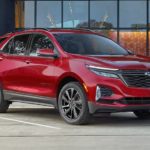A red 2022 Chevy Equinox RS is shown from the front parked in front of a modern building.