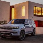 A silver 2021 Grand Wagoneer is parked outside of a modern house after winning a 2022 Grand Wagoneer vs 2021 Lexus GX comparison.