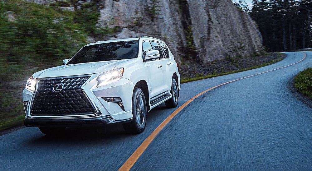 A white 2021 Lexus GX is shown driving past a rock face.