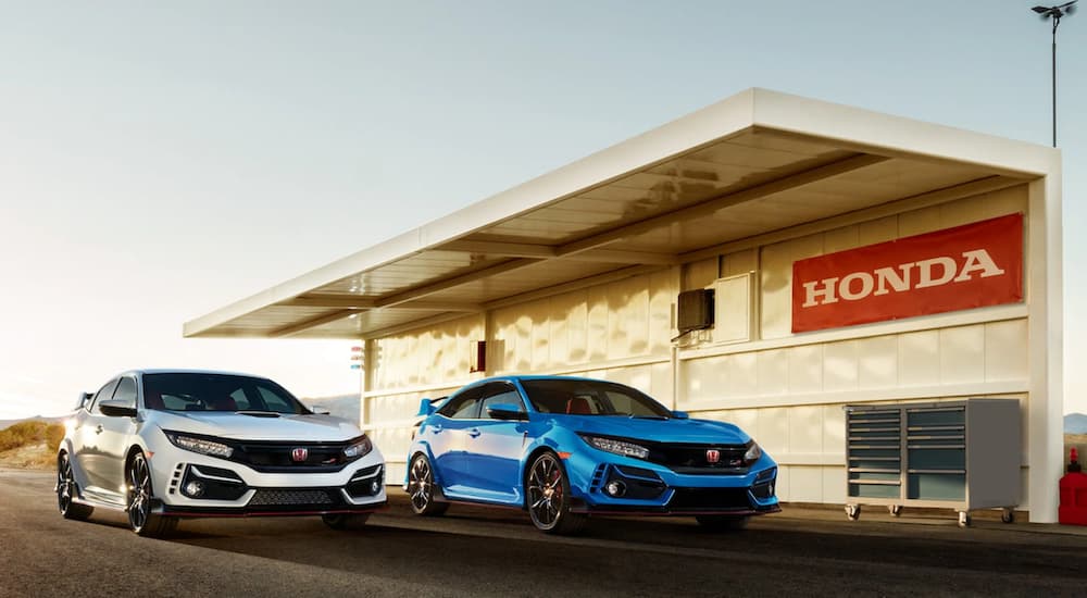 A white and a blue 2021 Honda Civic Type R are shown parked next to an awning and toolbox.