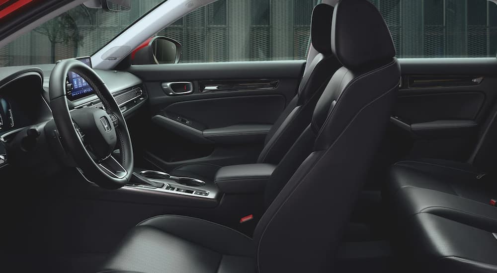 The black interior of a 2022 Honda Civic Touring shows the leather seats and steering wheel.