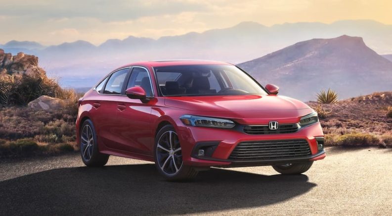 A red 2022 Honda Civic Touring is parked in front of the mountains at sunset after leaving a 2022 Honda Civic dealer.