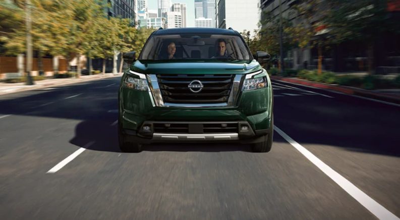 A green 2022 Nissan Pathfinder is shown from the front driving through a city.
