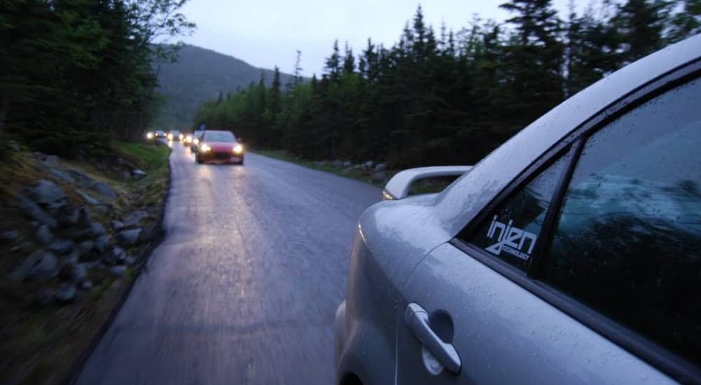 A Mazda6 is shown driving on a tree lined road at dusk.