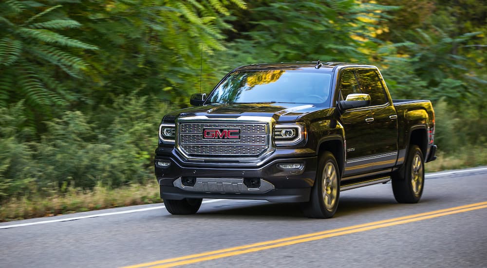 A black 2017 GMC Sierra 1500 Denali is shown driving down the road after visiting a used truck dealer.