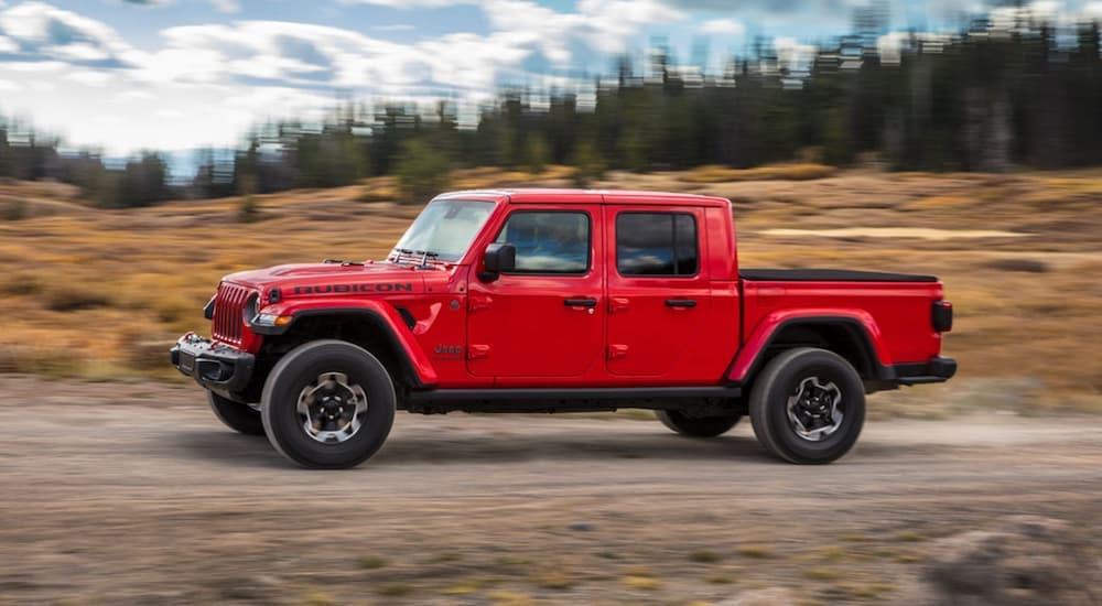 A red 2020 Jeep Gladiator is driving down a dirt road.