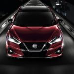 A red 2021 Nissan Maxima is shown from the front driving at night.
