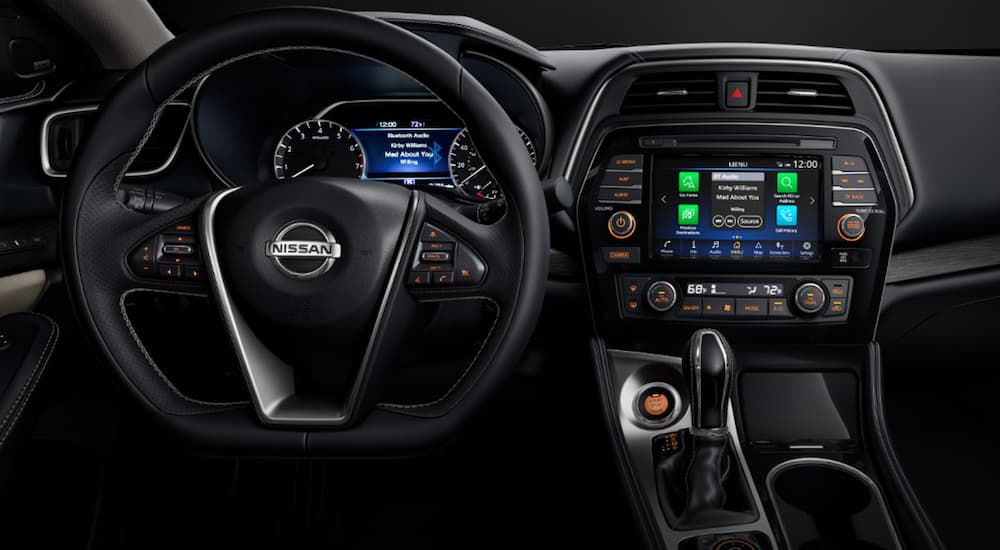 The interior of a 2021 Nissan Maxima shows the steering wheel and infotainment screen.